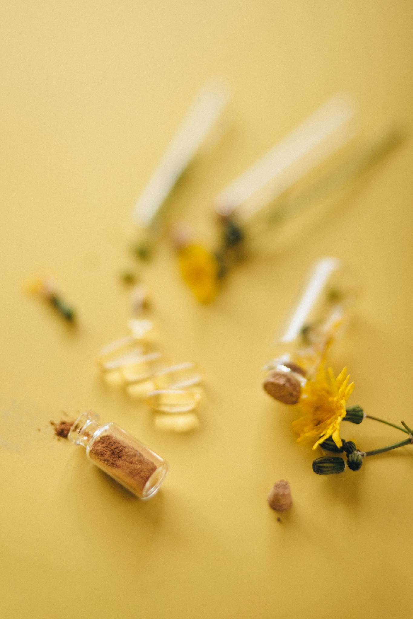 Close-up of herbal supplements with yellow flowers on a warm background.