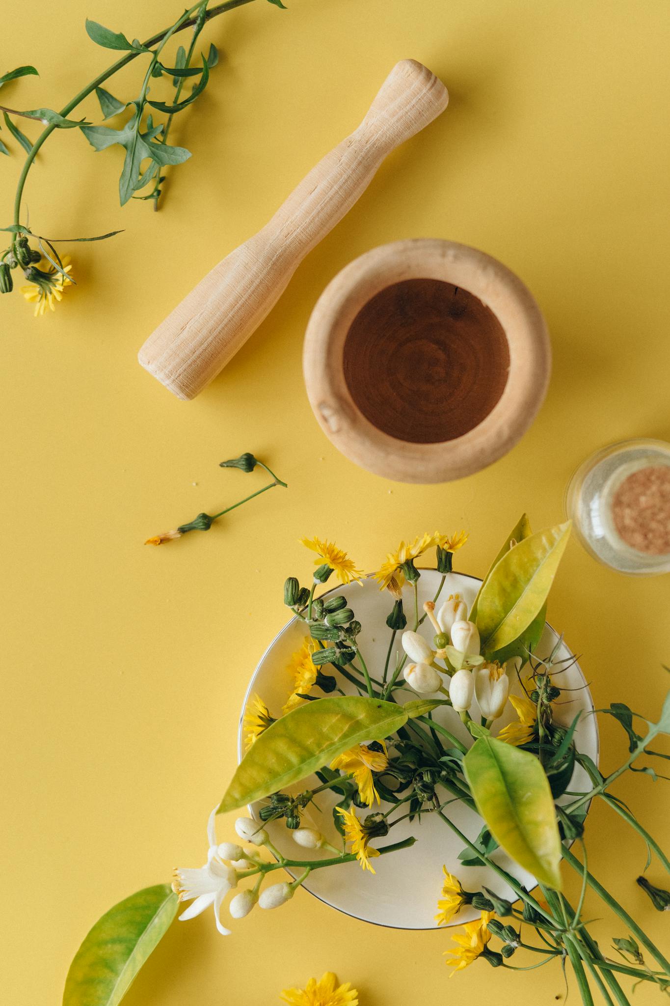Herbal ingredients with a mortar and pestle on yellow background, perfect for natural remedy concepts.